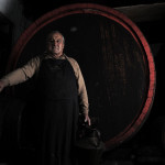 a Vernaccia wine producer in front of a giant barrel in his ancient cellar